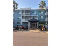 Inviting building entrance with covered walkway, lush landscaping, and swaying palm trees offering shade at 2755 Coconut Bay Ln # 1313 3M, Sarasota, FL 34237