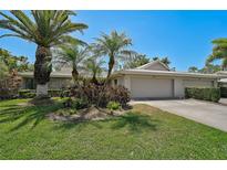 Charming single-story home featuring a tile roof, two-car garage, stone accents, and lush landscaping at 3890 Wilshire Cir # 27, Sarasota, FL 34238