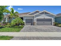 Charming home featuring a three-car garage, paver driveway, lush landscaping and well manicured lawn at 5793 Long Shore Loop, Sarasota, FL 34238