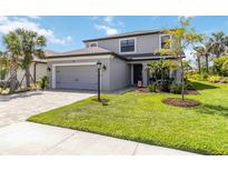 Charming two-story home with a well-manicured lawn, gray exterior, and a two-car garage at 9061 Luna Ln, Sarasota, FL 34241