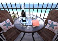 Balcony table set for a relaxing time, showcasing the beautiful ocean view at 1212 Benjamin Franklin Dr # 901, Sarasota, FL 34236