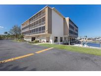Low angle view of a waterfront condo with parking, green space, and boat dock on a sunny day at 1714 69Th W Ave # C402, Bradenton, FL 34207