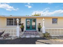 Charming home exterior with lush landscaping, decorative lamps, and inviting double door entrance at 2105 Georgia Ave, Englewood, FL 34224