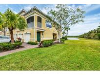 Charming yellow townhome featuring lush landscaping, a screened-in porch, and a beautiful waterfront view at 232 Explorer Dr # 15, Osprey, FL 34229