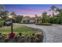 Elegant Mediterranean-style home featuring a circular driveway and lush landscaping at 3905 Trentwood Pl, Sarasota, FL 34243