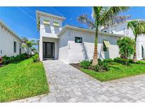 Beautiful white house with well manicured lawn and elegant brick driveway. Palm trees add tropical charm at 6028 Cat Claw Ln, Bradenton, FL 34210