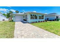 Inviting single-story home featuring a well-manicured lawn, paver driveway, and a charming light green exterior at 148 N Blvd Of The Presidents, Sarasota, FL 34236