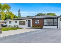 Charming single-story home with a well-manicured lawn and a modern white and wood facade at 1921 Fern Ave, Sarasota, FL 34235