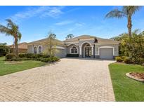 Beautiful single-story home with a brick driveway, gray facade, and lush landscaping at 19798 Cobblestone Cir, Venice, FL 34292