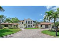 Stunning two-story home with a clay tile roof and circular driveway, surrounded by lush landscaping at 2833 Bay Shore Cir, Sarasota, FL 34234