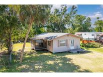 Charming single-story home featuring a screened porch and a lush green lawn with mature trees at 409 Olive Ave, Nokomis, FL 34275