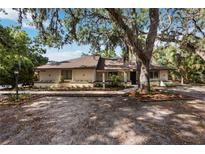 Single story home with desert landscaping in front of the house and mature trees creating shade at 4916 Hidden Oaks Trl, Sarasota, FL 34232