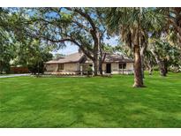 Charming home with a lush green lawn and mature trees offering ample shade at 4916 Hidden Oaks Trl, Sarasota, FL 34232