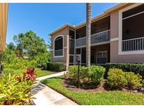 Charming condo building featuring lush landscaping, screened balconies, and a well-maintained walkway under a clear blue sky at 5251 Mahogany Run Ave # 521, Sarasota, FL 34241