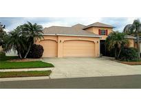 Inviting home featuring a three car garage, neutral stucco, well-kept lawn and tropical palm trees at 6631 63Rd E Ter, Bradenton, FL 34203