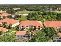 An aerial view showing the building with a red tile roof next to a golf course and mature Florida landscape at 7115 Boca Grove Pl # 204, Lakewood Ranch, FL 34202