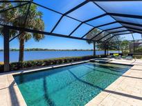 Gorgeous screened pool with lake view, lush landscaping, and ample seating at 7864 Grande Shores Dr, Sarasota, FL 34240