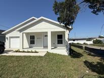 Charming single-story home featuring a well-manicured lawn, attached garage, and a freshly painted exterior at 8810 1/2 N Mulberry St, Tampa, FL 33604