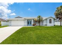 Charming single-story home with well-manicured lawn, blue double doors, and attached two car garage at 11895 Claremont Dr, Port Charlotte, FL 33981