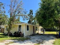 Quaint single-story home featuring a stucco exterior, mature trees, and a gravel driveway at 1317 Venetia St, Nokomis, FL 34275