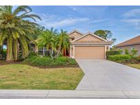 Charming single-story home with a well-manicured lawn, complemented by lush tropical landscaping and an attached two-car garage at 1363 New Forest Ln, Osprey, FL 34229