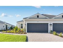 Beautiful home exterior with a two-car garage, brick paved driveway, and landscaped lawn at 16202 Isola Pl, Bradenton, FL 34211