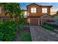 Charming two-story townhome featuring a well-manicured lawn, paver driveway, and attached garage at 20228 Lagente Cir, Venice, FL 34293