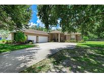 Spacious home exterior with a long driveway, mature trees, green grass, and a two-car garage at 2611 221St E St, Bradenton, FL 34211