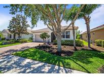 Charming single-story home with a well-manicured lawn, mature trees, and a paver driveway at 358 River Enclave Ct, Bradenton, FL 34212