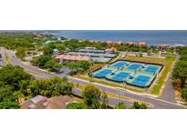 An aerial view showcasing multiple tennis courts next to the Gulf of Mexico and nearby condominiums at 4510 El Conquistador Pkwy # 105, Bradenton, FL 34210