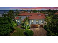 Aerial view of a waterfront Mediterranean home with a tile roof, three-car garage and lush landscaping at 524 Schooner Ln, Longboat Key, FL 34228