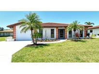 Charming single-story home with a red tile roof, a well-manicured lawn, and lush palm trees at 6007 Vivienda Dr # 29, Bradenton, FL 34207