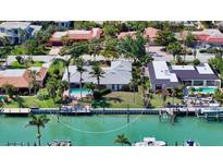 Waterfront home features a private dock, backyard pool, and lush tropical landscaping at 642 S Owl Dr, Sarasota, FL 34236