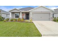 Charming single-story home with a well-manicured lawn, two-car garage, and inviting front porch at 6708 162Nd E Pl, Parrish, FL 34219