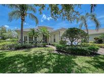 Charming single-story home with tile roof, lush landscaping, and mature palm trees in a well-manicured front yard at 7528 Ascot Ct, University Park, FL 34201