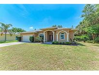Charming home featuring a well-manicured lawn, arched entryway, and a welcoming red front door at 1631 Madison Ave, North Port, FL 34286