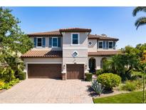 Stately two-story home with a three-car garage, tile roof, lush landscaping, and a brick paved driveway at 1719 Kenilworth St, Sarasota, FL 34231