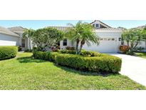 Beautifully landscaped front yard with lush green bushes, palm trees and a manicured lawn at 3870 Alamanda Dr, Sarasota, FL 34238