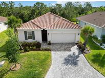 Beautiful single-story home with a red tile roof, manicured landscaping, and a paver driveway at 412 Daylily Blvd, Nokomis, FL 34275