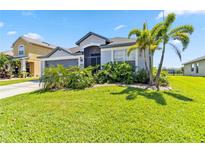Well-manicured front lawn and garden surrounding a lovely single-story home with gray garage at 5919 100Th E Ave, Parrish, FL 34219