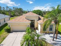 Beautiful home featuring a tan exterior, a two-car garage, palm trees, and manicured landscaping at 6838 44Th E Ter, Bradenton, FL 34203