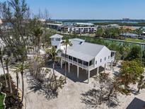 Stunning elevated home features a modern design, metal roof, and wraparound porch, nestled amid lush landscaping at 9265 Blind Pass Rd, Sarasota, FL 34242