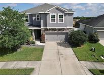 Charming two-story home with a stone-accented facade, landscaped yard, and a spacious driveway at 10934 79Th E St, Parrish, FL 34219