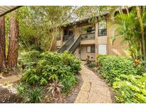 Charming two-story condo with lush landscaping and a stone pathway leading to the entrance at 1711 Pelican Cove Rd # 443, Sarasota, FL 34231