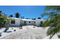 Charming single-story home featuring a lush, landscaped front yard and a brightly colored front door at 306 Island Cir, Sarasota, FL 34242