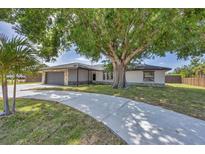 Charming home featuring a stone-accented facade, attached garage, and a spacious, curved driveway, all shaded by a mature tree at 3136 Webber St, Sarasota, FL 34239