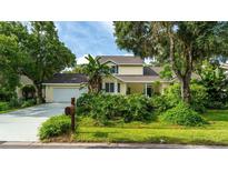 Charming two-story home featuring a manicured lawn, mature trees, and an attached two-car garage at 4326 Brackenwood Ct, Sarasota, FL 34232