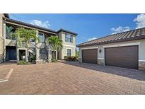 Elegant building featuring lush landscaping, private garages, and paver driveway at 5424 Cicerone St # 204, Sarasota, FL 34238