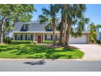 Charming home featuring a landscaped yard, palm trees, black shutters, and a bright red front door at 5504 Beneva Woods Circle, Sarasota, FL 34233