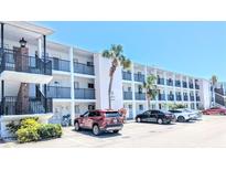 A clean three-story condo building with black wrought iron railings and covered parking on a bright, sunny day at 5901 Garden Ln # H23, Bradenton, FL 34207